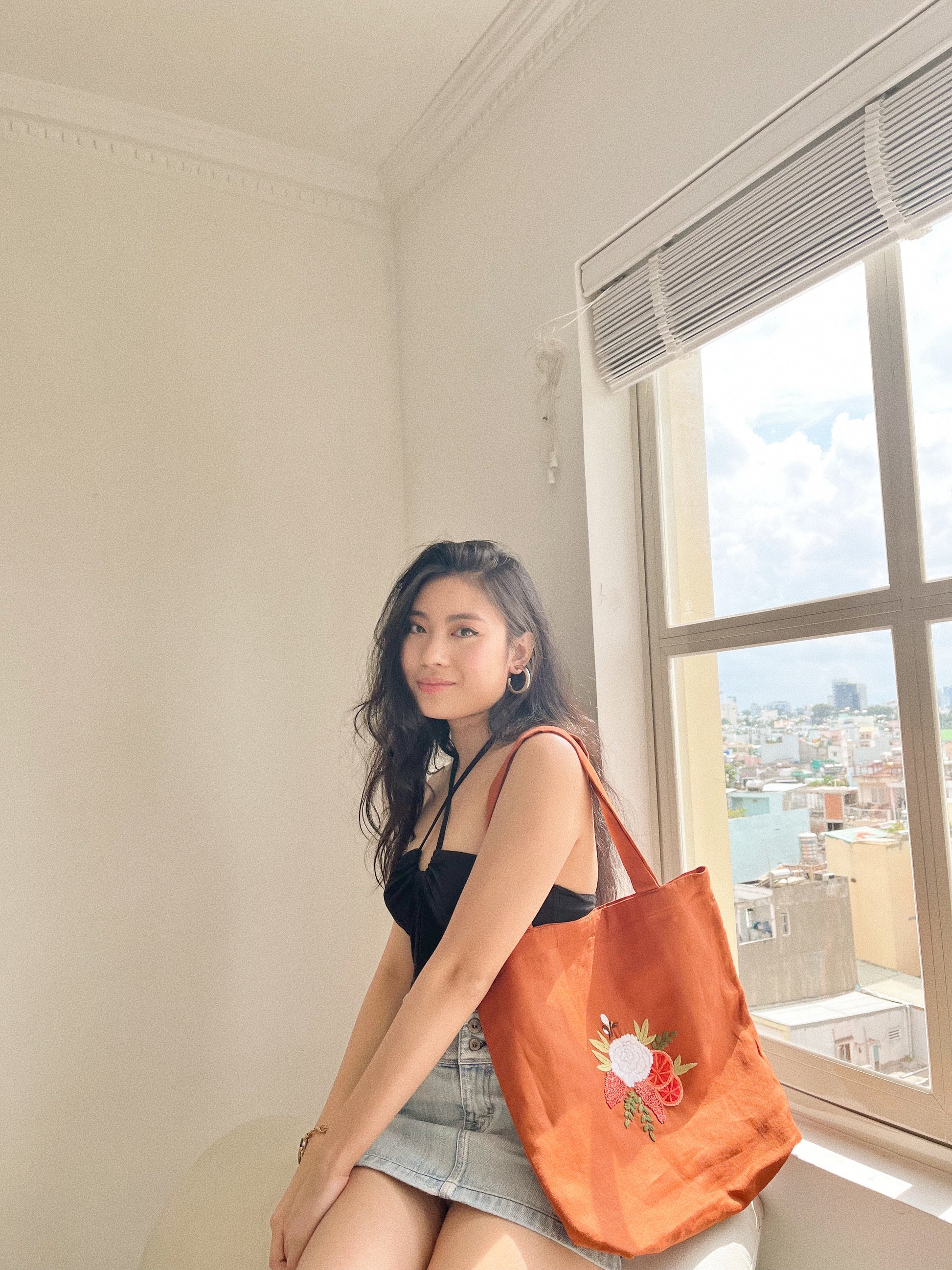 Hand embroidered linen tote bag with bee above a flower embroidery.